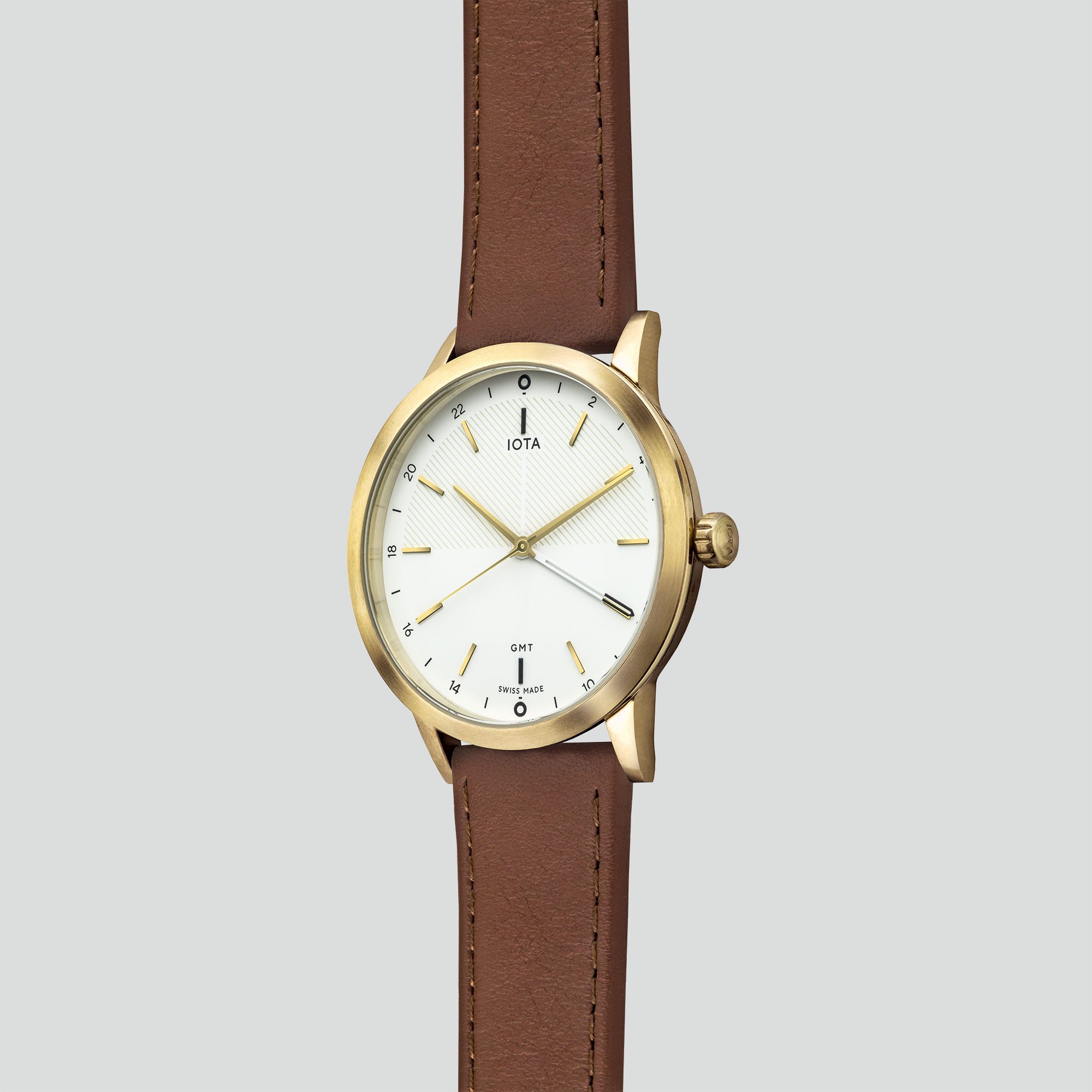 A side profile of the IOTA New York GMT watch with white dial, gold PVD brushed and polished 316L stainless steel case housing a tan nappa leather watch strap