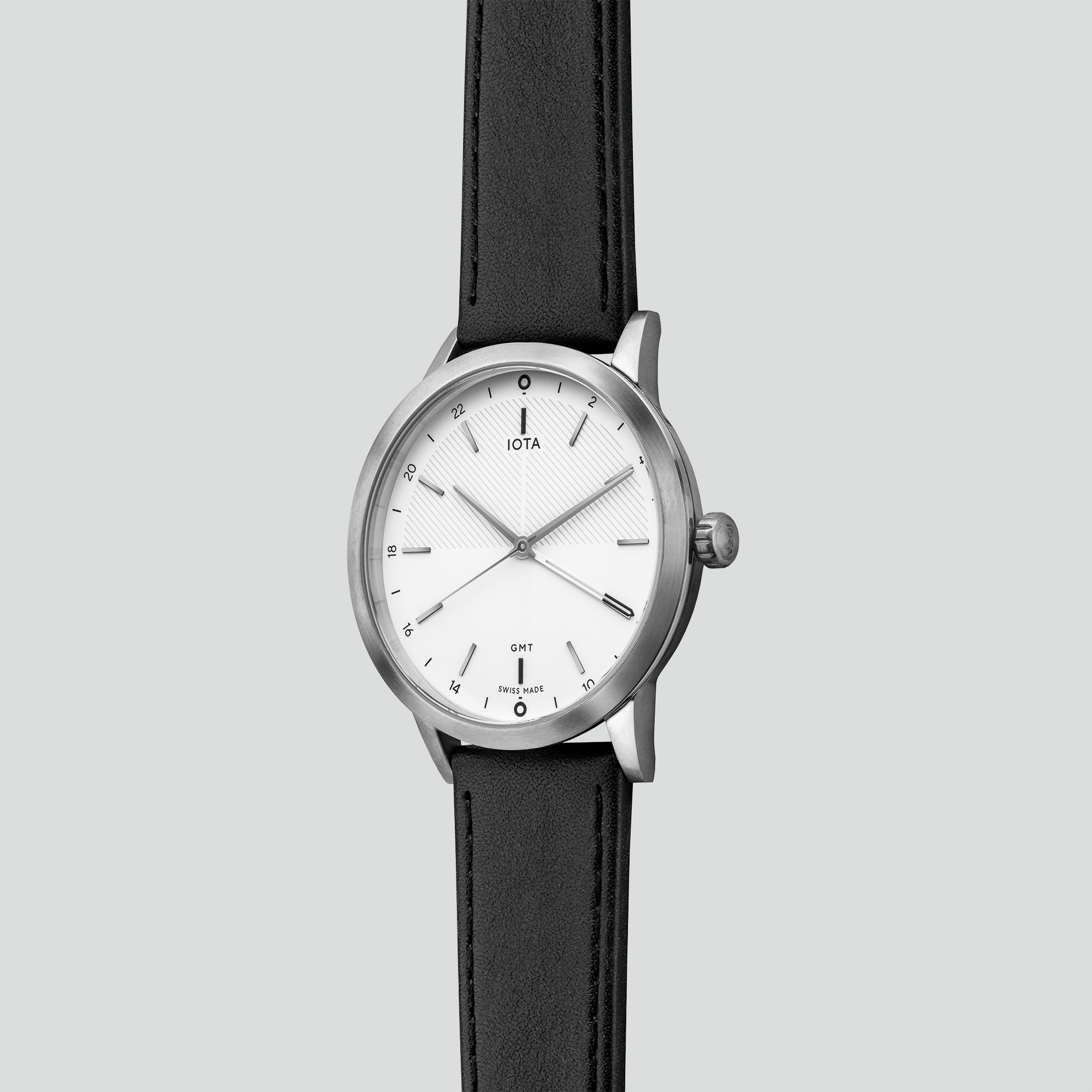 A side profile of the IOTA London GMT watch with white dial, brushed and polished 316L stainless steel case housing a black nappa leather watch strap